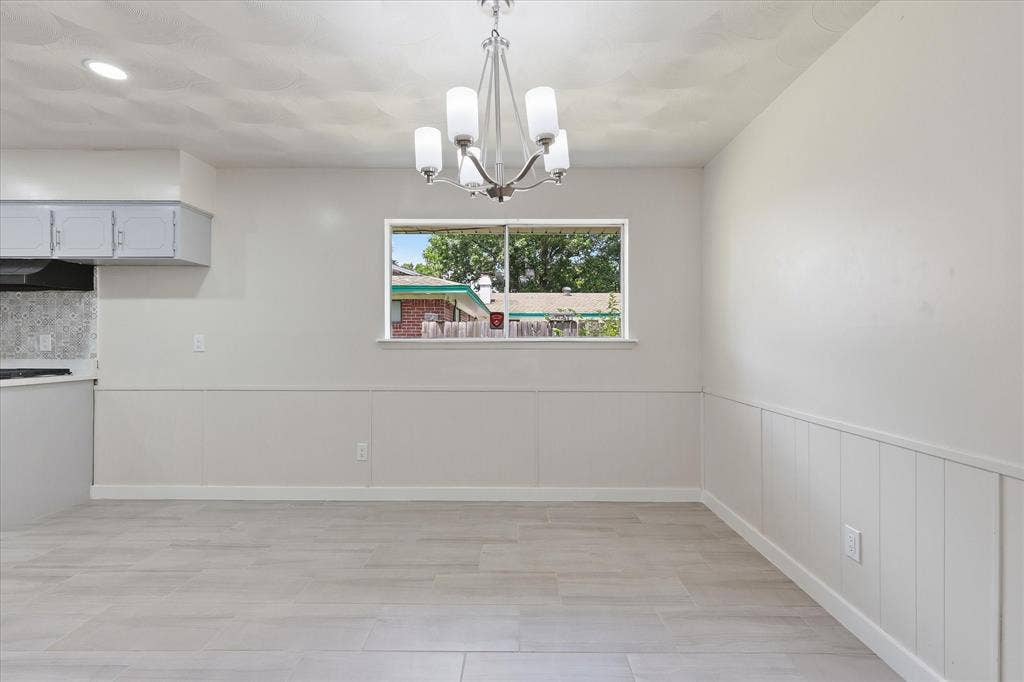 3301 Hillsdale Lane, Garland, TX 75042 Dining area featuring a contemporary chandelier, light-toned wood-look tile flooring, and a window providing natural light