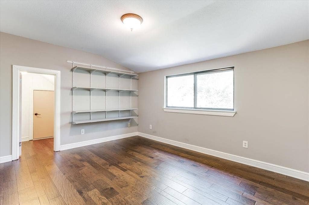 Room featuring wood-finish flooring, a vaulted ceiling, and built-in shelving