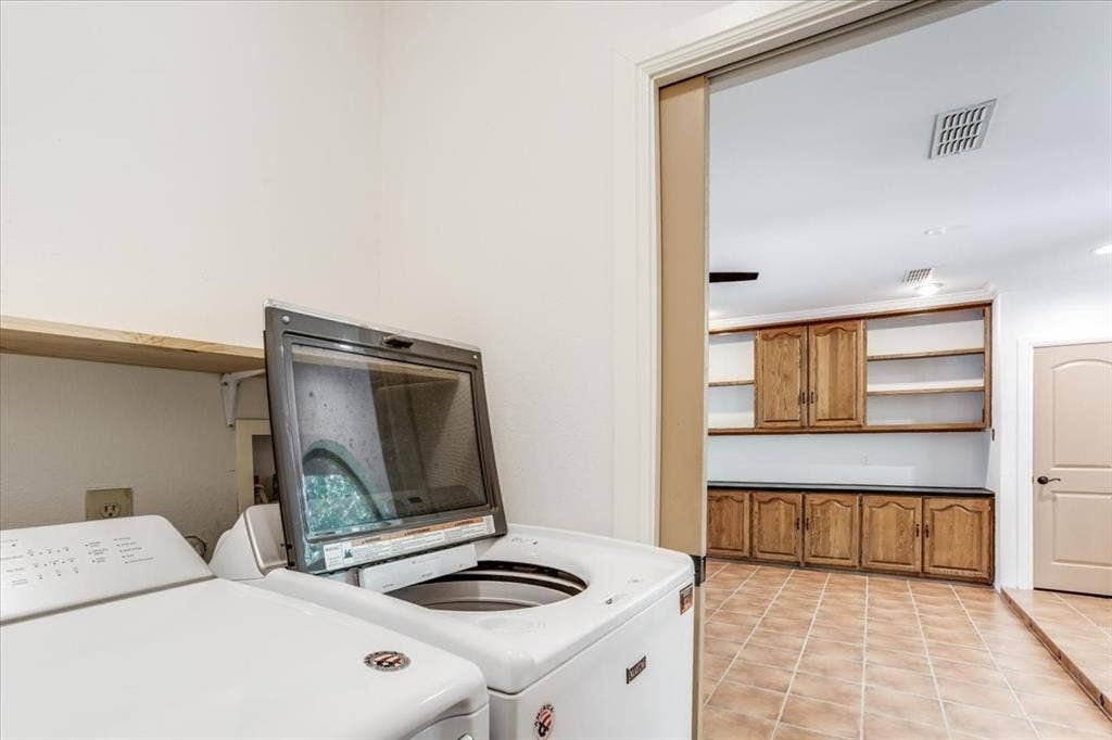Utility space featuring a wood shelf and an adjacent room with extensive built-in wooden cabinetry, open shelving, and tile flooring