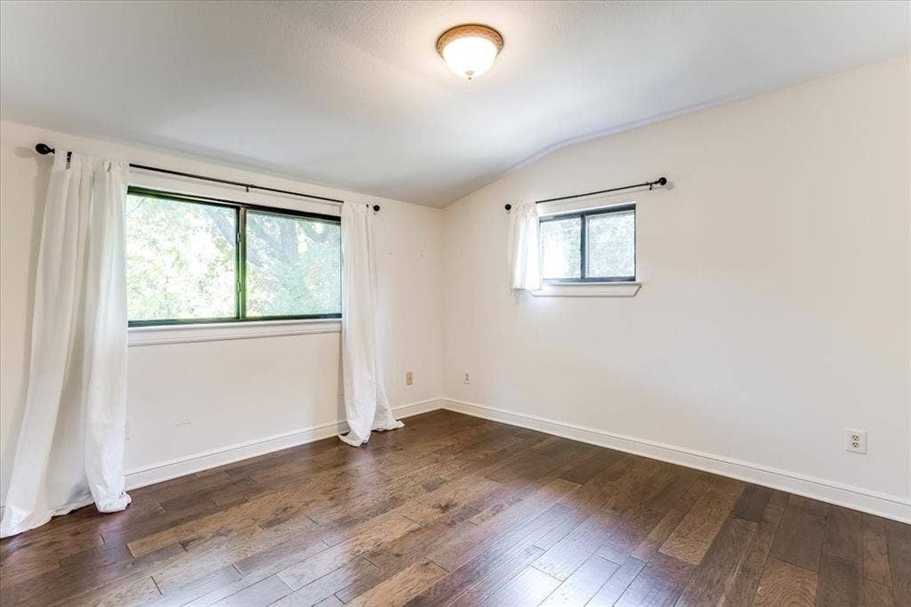 Room featuring wood-finish flooring, white walls, and white baseboards