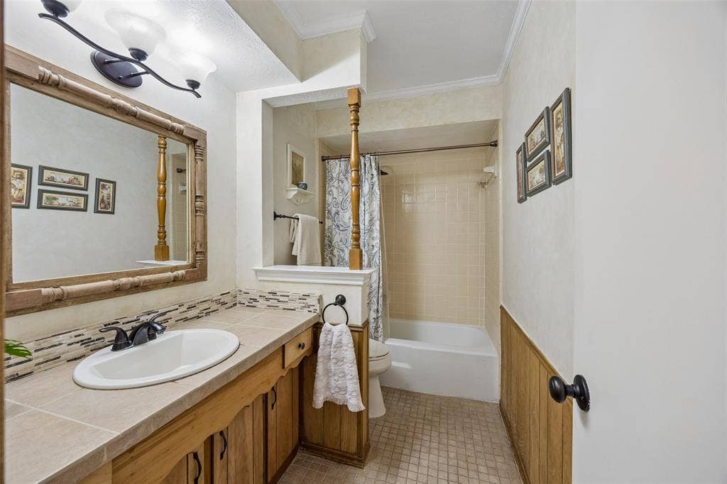2104 Westlake Drive, Plano, TX 75075 Bathroom featuring a single vanity with wood cabinetry, a light-toned countertop, and a tiled backsplash