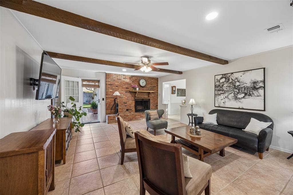 2104 Westlake Drive, Plano, TX 75075 Spacious living area featuring exposed wood beams, a brick fireplace, and tiled flooring.