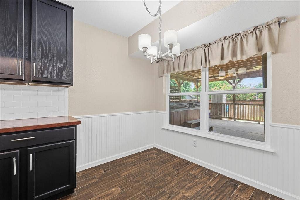 6572 Ridglea Drive, Watauga, TX 76148 Dining area featuring wood-finish flooring, wainscoting, and a multi-pane window