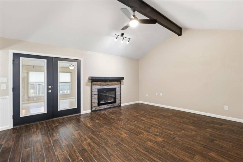 6572 Ridglea Drive, Watauga, TX 76148 Spacious living area featuring wood-finish flooring, a vaulted ceiling with exposed beam, and a ceiling fan