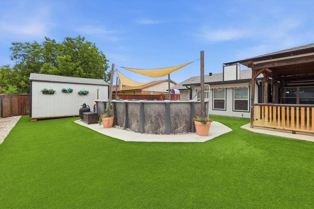 6572 Ridglea Drive, Watauga, TX 76148 Expansive backyard featuring artificial turf, an above-ground pool with shade sails, a freestanding storage shed, and a wooden gazebo