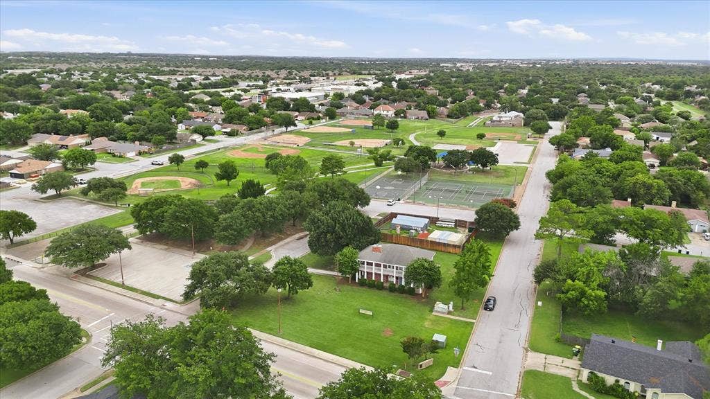6572 Ridglea Drive, Watauga, TX 76148 Two-story white residence featuring a red roof and prominent white columns, situated on a substantial green lawn