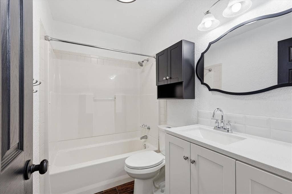 6572 Ridglea Drive, Watauga, TX 76148 Bathroom featuring a white vanity with cabinet storage, a decorative framed mirror, and chrome fixtures