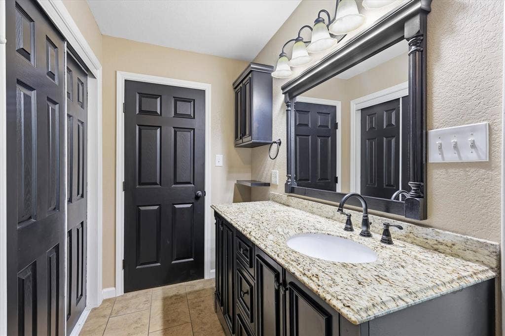 6572 Ridglea Drive, Watauga, TX 76148 Bathroom vanity with a granite countertop and an integrated white sink