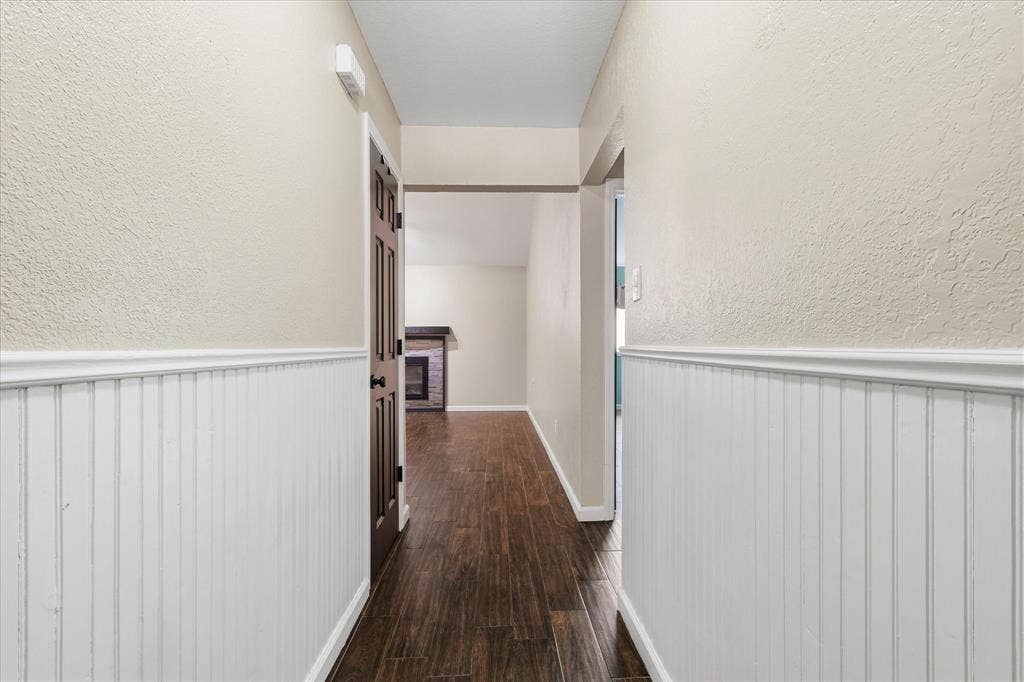6572 Ridglea Drive, Watauga, TX 76148 Hallway featuring wainscoting, wood-finish flooring, and neutral wall tones