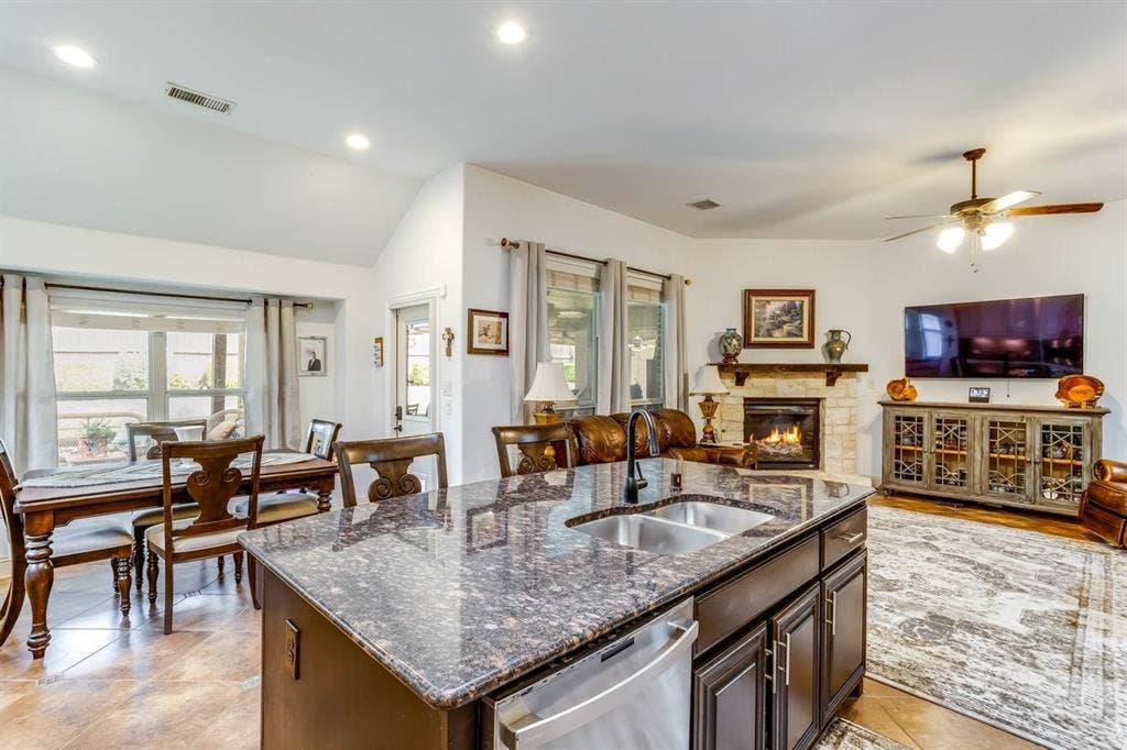 114 Lyndhurst Drive, Wylie, TX 75098 Kitchen island with dark cabinetry and a speckled countertop, featuring an undermount double-basin stainless steel sink