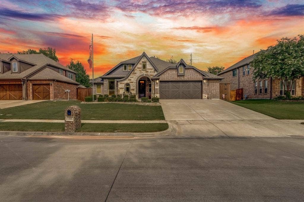 114 Lyndhurst Drive, Wylie, TX 75098 Exterior featuring a stone and brick facade, arched entry, two-car garage with a decorative door, concrete driveway, and a manicured lawn
