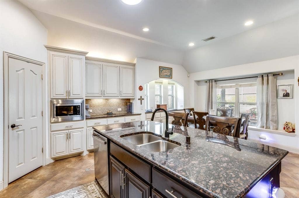 114 Lyndhurst Drive, Wylie, TX 75098 Kitchen featuring a large island with a double basin sink, granite countertops, light wood-finish cabinetry, and stainless steel appliances