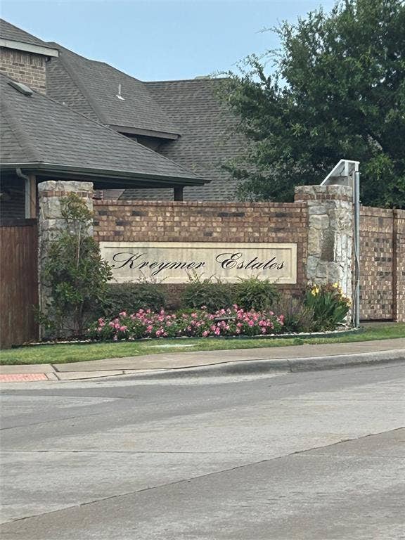 114 Lyndhurst Drive, Wylie, TX 75098 Stone and brick entryway signage featuring "Kreymer Estates" inscription, surrounded by lush landscaping and flowering pink plants