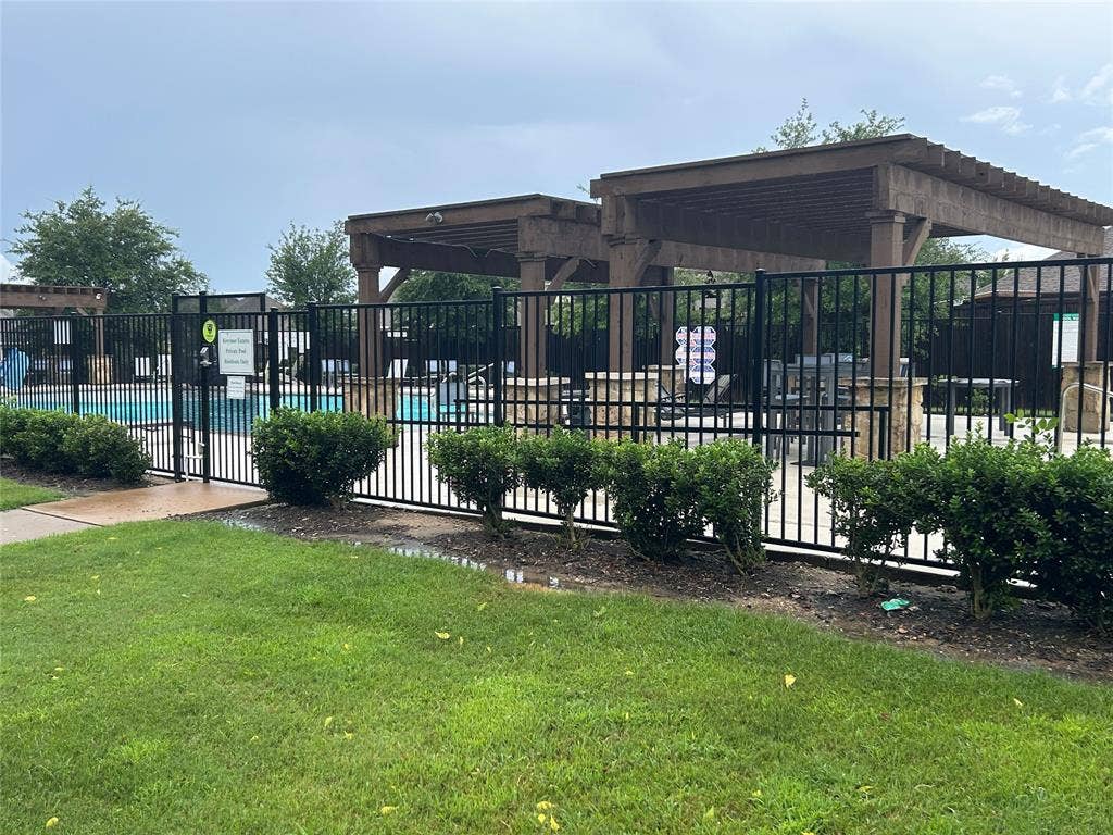 114 Lyndhurst Drive, Wylie, TX 75098 Outdoor pool area featuring black wrought iron fencing, multiple pergolas, and stone pillar accents