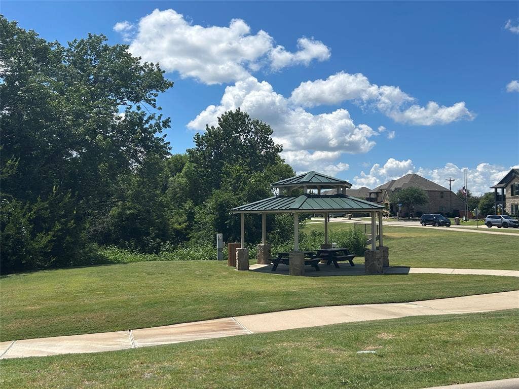 114 Lyndhurst Drive, Wylie, TX 75098 Community gazebo with a tiered green roof, stone-clad pillars, and a picnic table