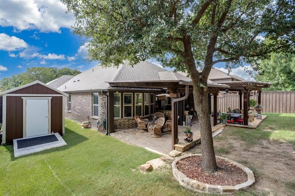 114 Lyndhurst Drive, Wylie, TX 75098 Expansive backyard featuring a stone patio, large pergola, and mature trees