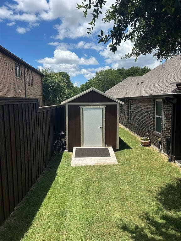 114 Lyndhurst Drive, Wylie, TX 75098 Backyard storage shed with a light-colored door, dark siding, and a gabled roof