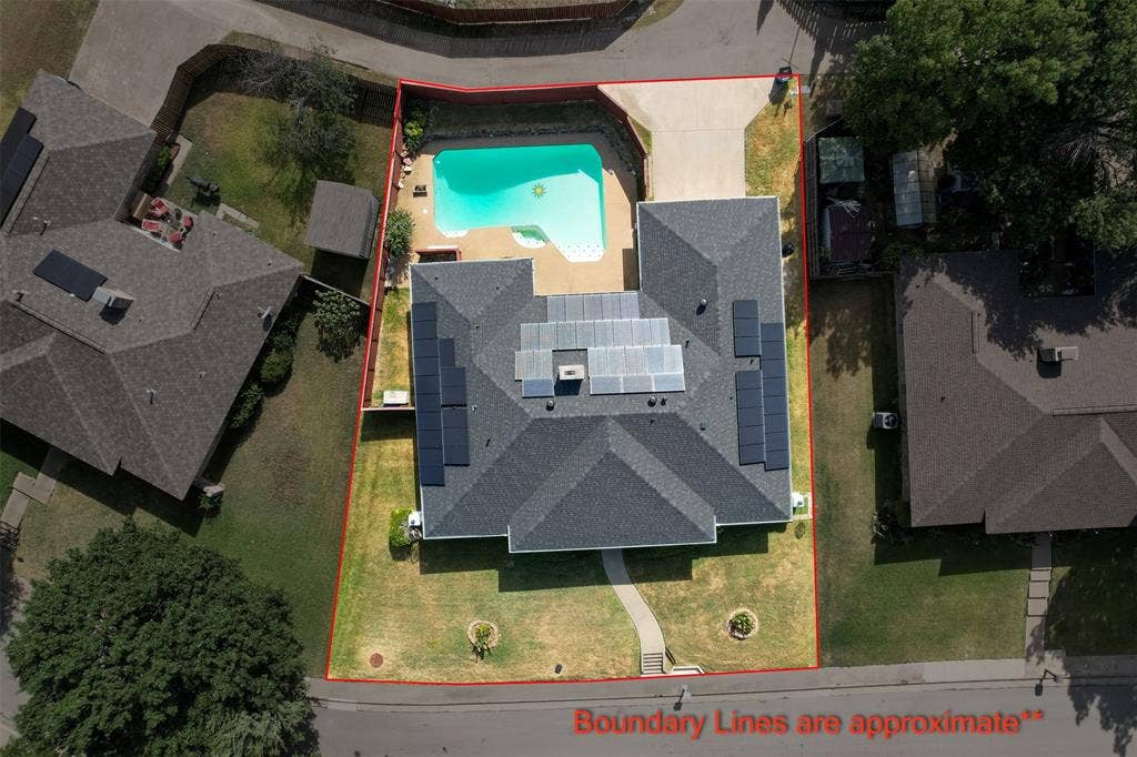 1315 Winding Brook Drive, DeSoto, TX 75115 Shingled roof with solar panels, backyard swimming pool, concrete pool deck, attached driveway, and a manicured lawn