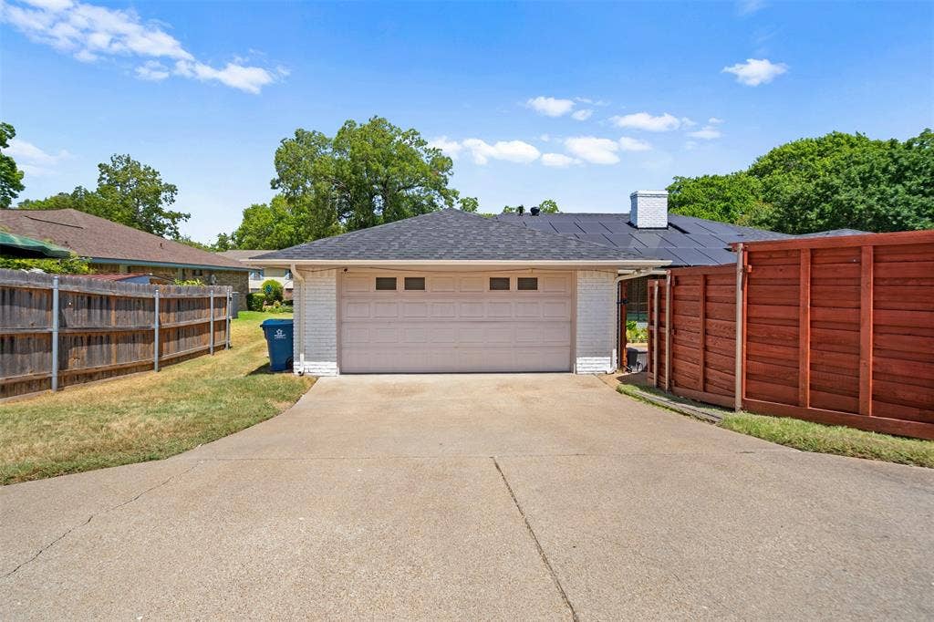 1315 Winding Brook Drive, DeSoto, TX 75115 Attached two-car garage with a concrete driveway, white brick exterior, and a dark shingle roof