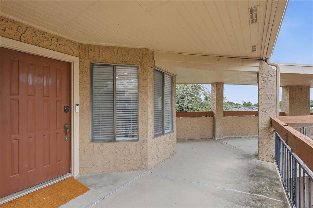 5550 Spring Valley Road, #A31, Dallas, TX 75254 Covered outdoor patio with textured stucco walls, a paneled entry door, and integrated window blinds