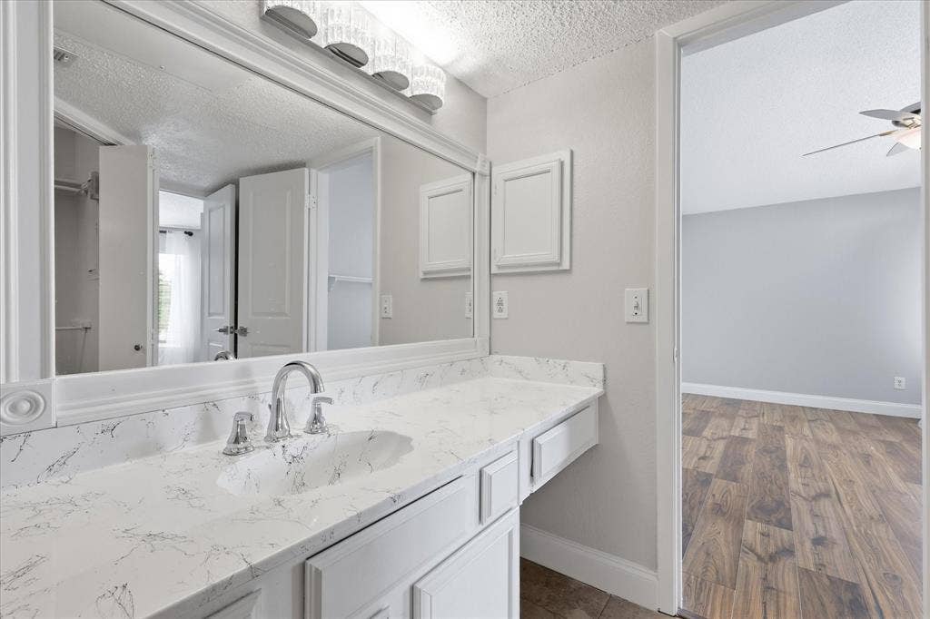 5550 Spring Valley Road, #A31, Dallas, TX 75254 Bathroom vanity featuring a polished chrome faucet, white countertop with integrated sink, and a large framed mirror