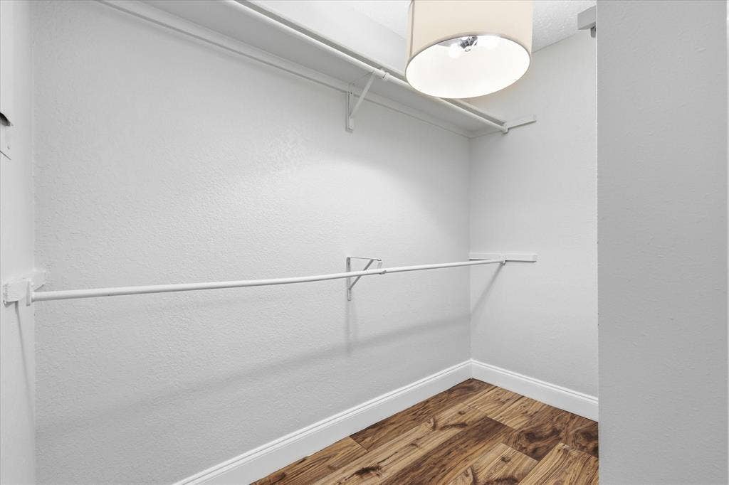 5550 Spring Valley Road, #A31, Dallas, TX 75254 Walk-in closet featuring wood-finish flooring, white walls, built-in shelving, a hanging rod, and a ceiling-mounted light fixture