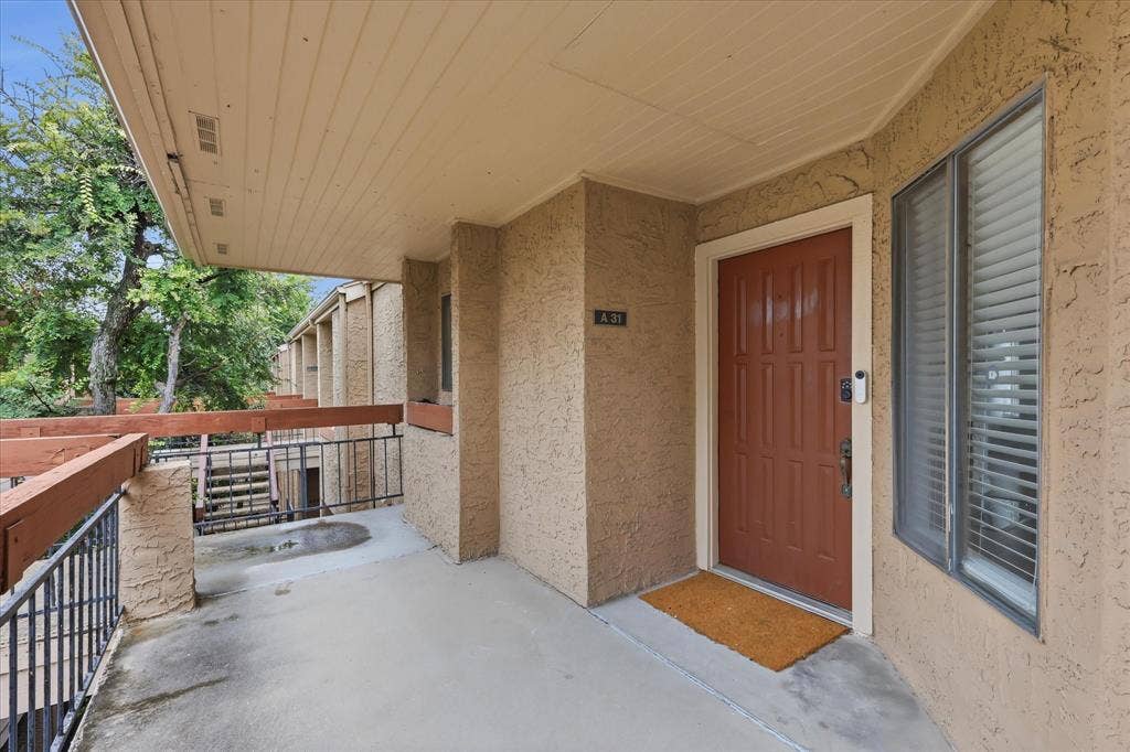 5550 Spring Valley Road, #A31, Dallas, TX 75254 Covered entry with textured stucco exterior, an insulated paneled door, and a multi-pane window with blinds