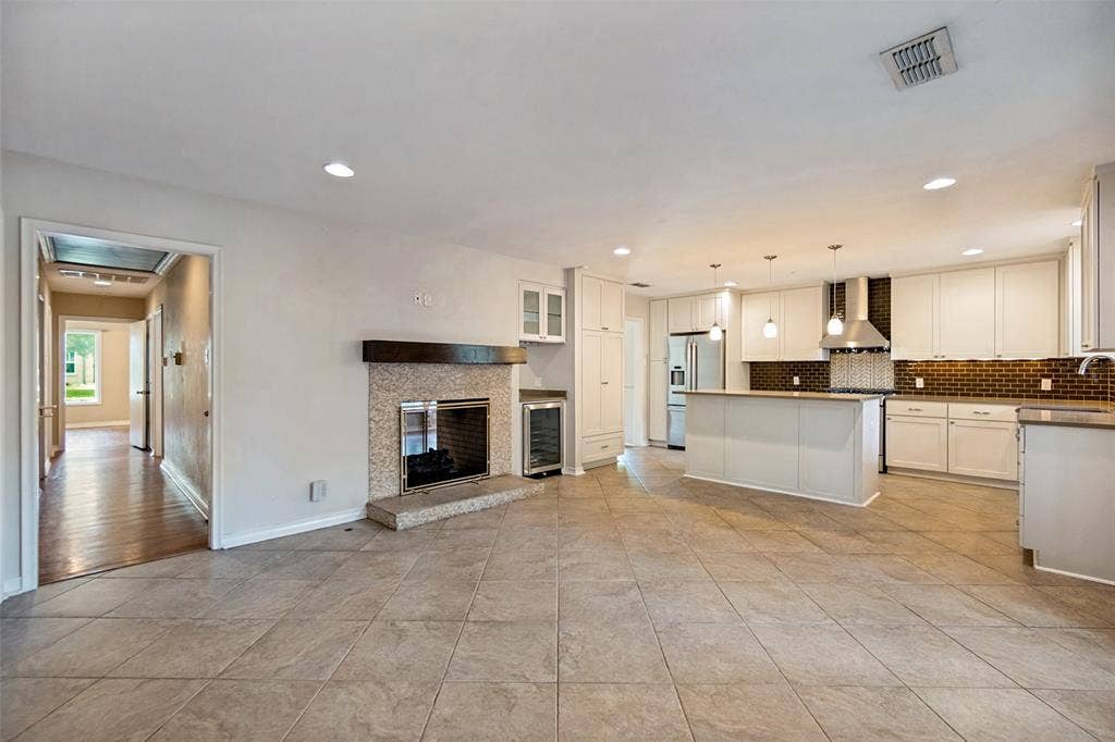 Island provides space for bar top dining. Open floor plan showing den with kitchen and hallway to bedrooms.