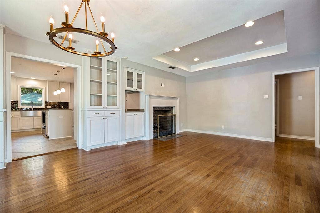 Designer light fixture in dining which connects to updated kitchen. Tray ceiling with can lighting in living room.