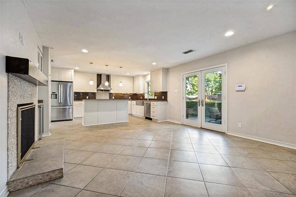 Ceramic tile floors from den into kitchen. Double French doors to backyard space. Stone fire place surround and wood beam mantle.