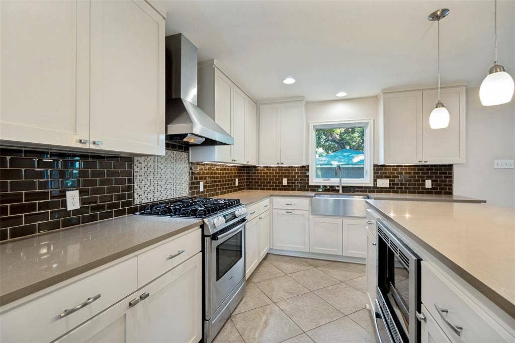 Stainless farmhouse sink. Ceramic backsplash with mosaic range details