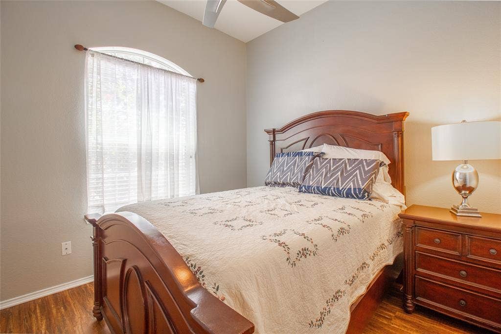 406 Hackberry Drive, Fate, TX 75087 Bedroom featuring wood-finish flooring, a vaulted ceiling, and an arched window with blinds