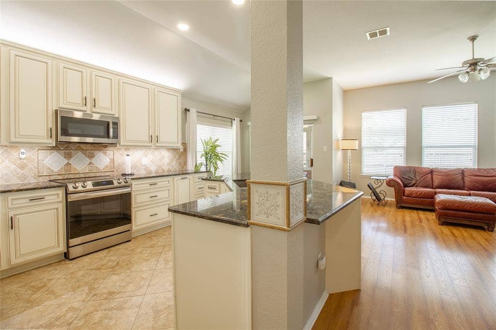 406 Hackberry Drive, Fate, TX 75087 Kitchen with cream-finished cabinetry, stainless steel appliances, and granite countertops