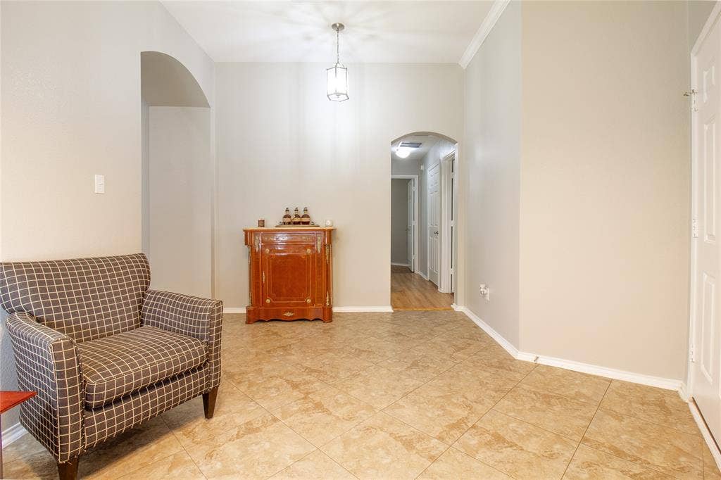 406 Hackberry Drive, Fate, TX 75087 Warm neutral wall tones with crown molding, square tile flooring, and arched doorways