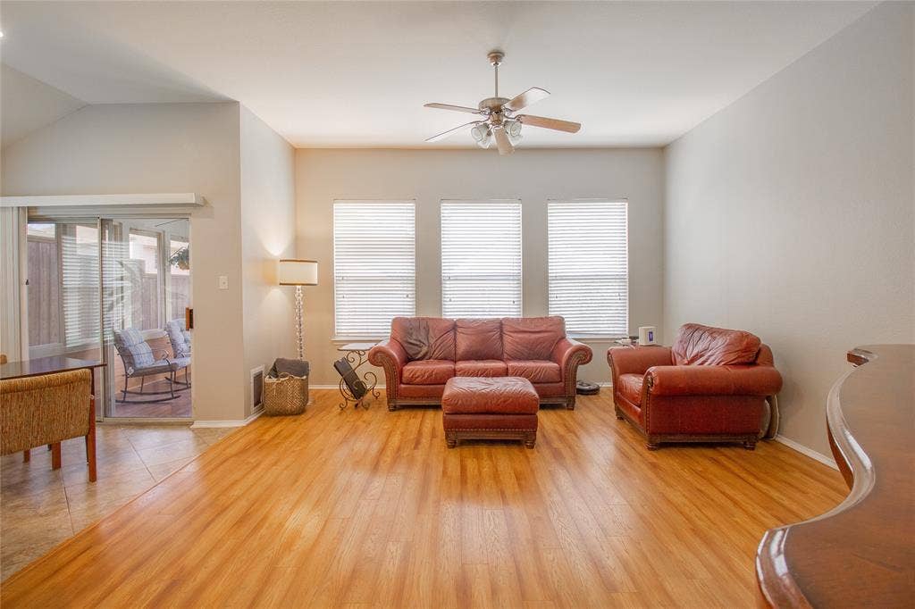 406 Hackberry Drive, Fate, TX 75087 Living area featuring wood-finish flooring, a vaulted ceiling, and a ceiling fan with integrated lighting