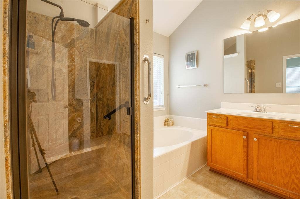 406 Hackberry Drive, Fate, TX 75087 Glass-enclosed shower featuring natural stone walls and a built-in bench