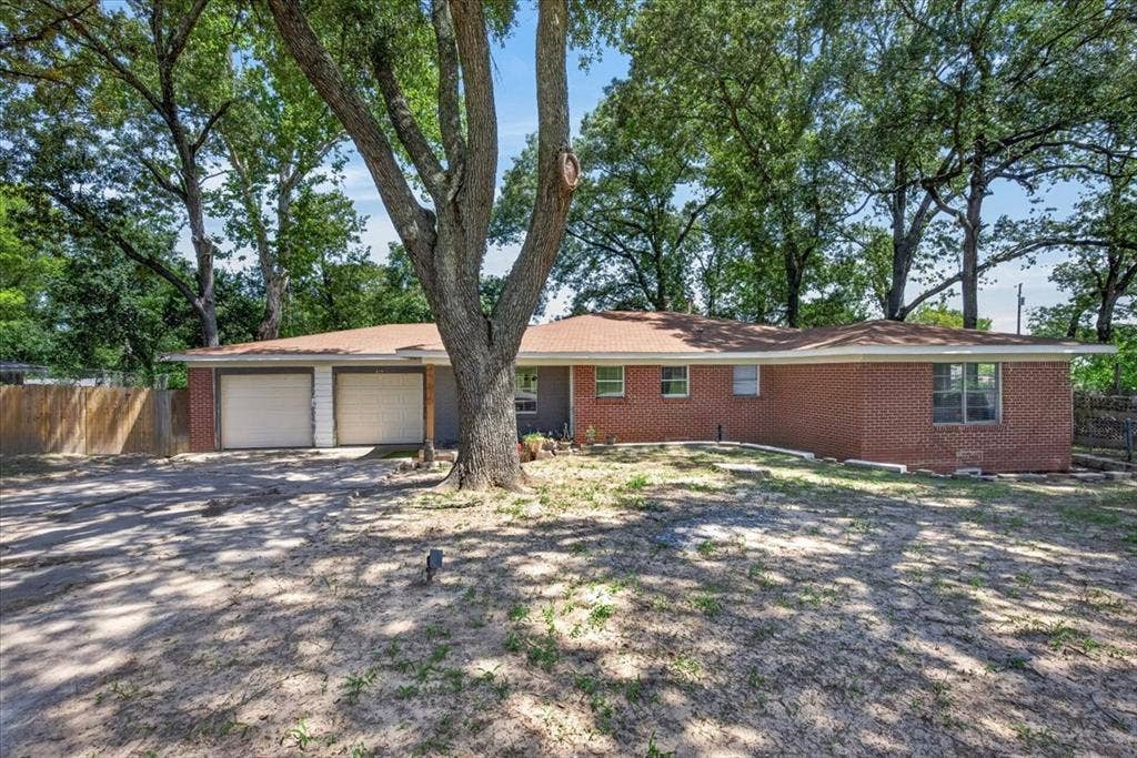 925 Maryland Drive, Athens, TX 75751 Brick exterior residence featuring a two-car garage, mature trees, and a partially fenced perimeter