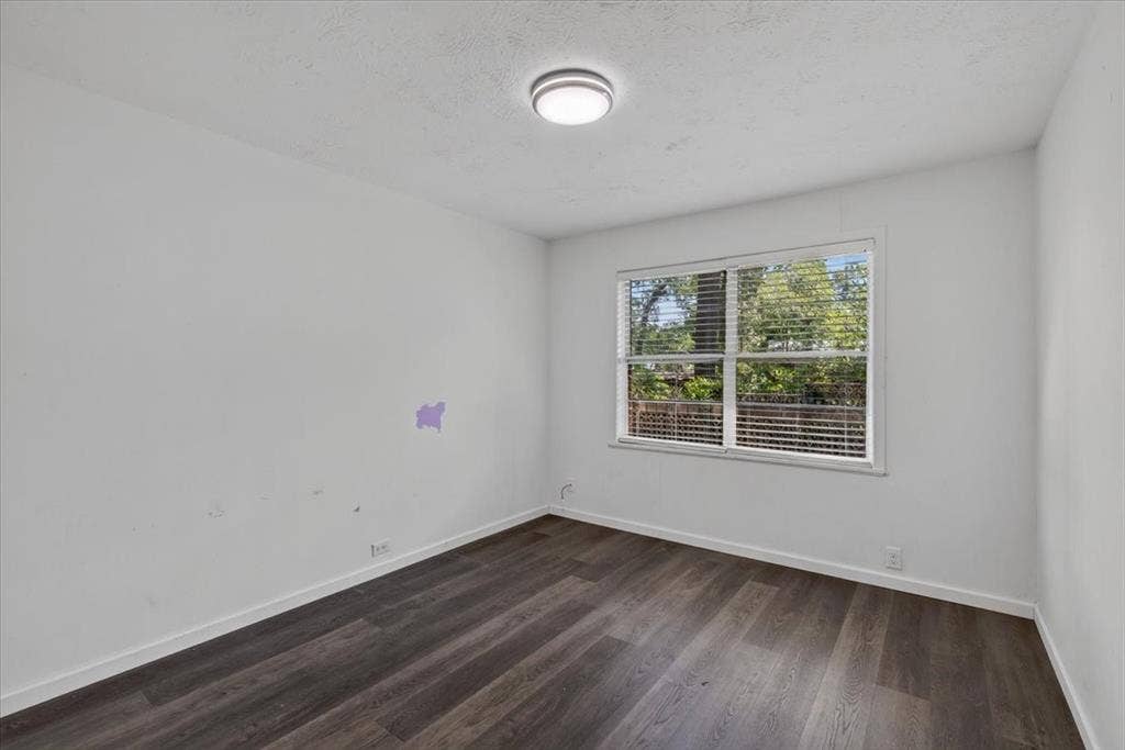 925 Maryland Drive, Athens, TX 75751 Room featuring wood-finish flooring, white baseboards, a white ceiling with a flush-mount light fixture, and a window with horizontal blinds
