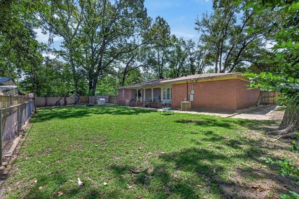 925 Maryland Drive, Athens, TX 75751 Expansive backyard featuring a manicured lawn, established shade trees, and a red brick exterior