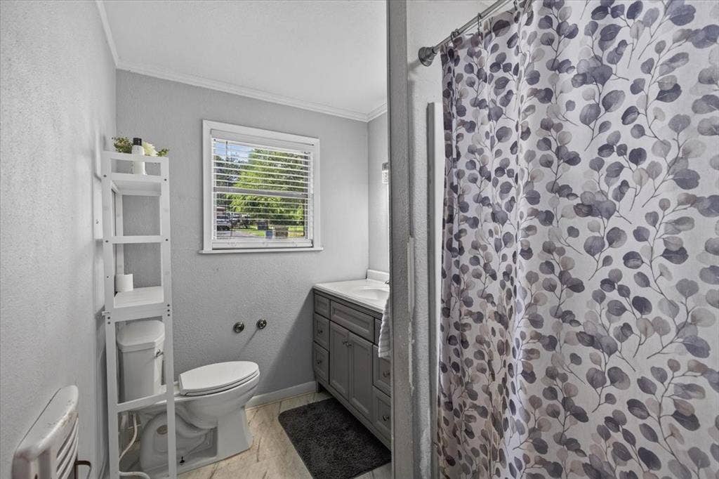 925 Maryland Drive, Athens, TX 75751 Bathroom featuring a window with blinds, a toilet, a vanity with a countertop and sink, and a shower area with a shower curtain