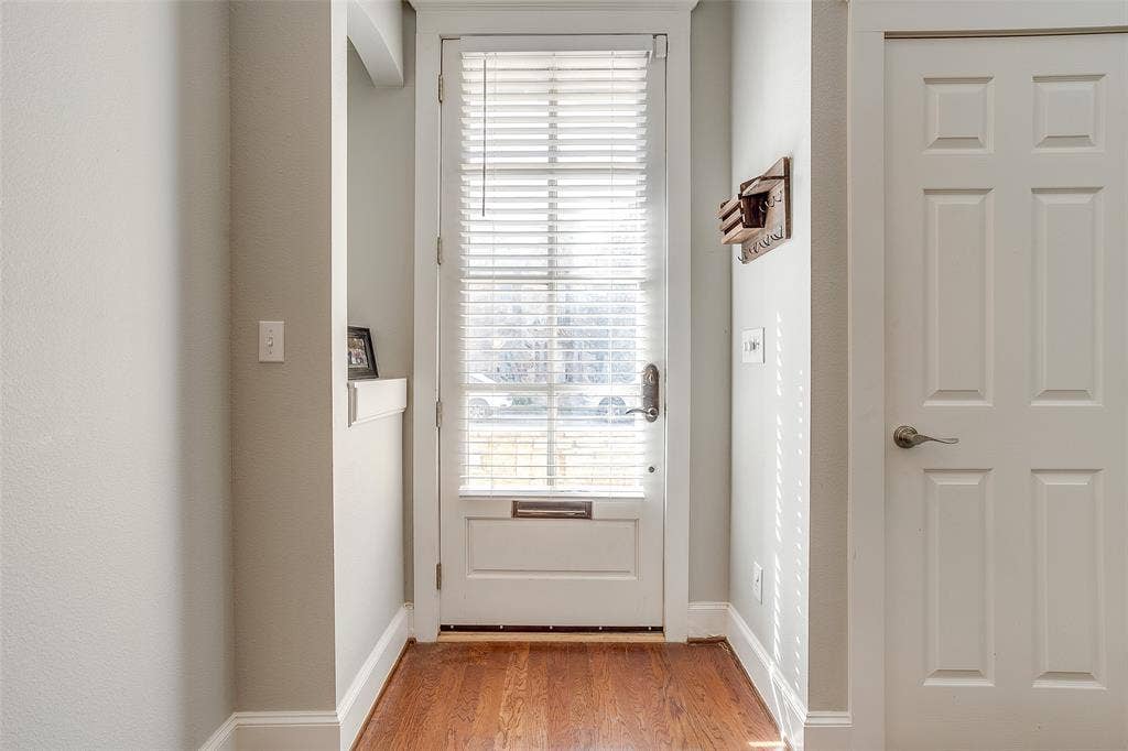 1211 S Adams Street, Fort Worth, TX 76104 Entryway featuring wood-finish flooring, a white paneled door, and a built-in wall niche with shelving