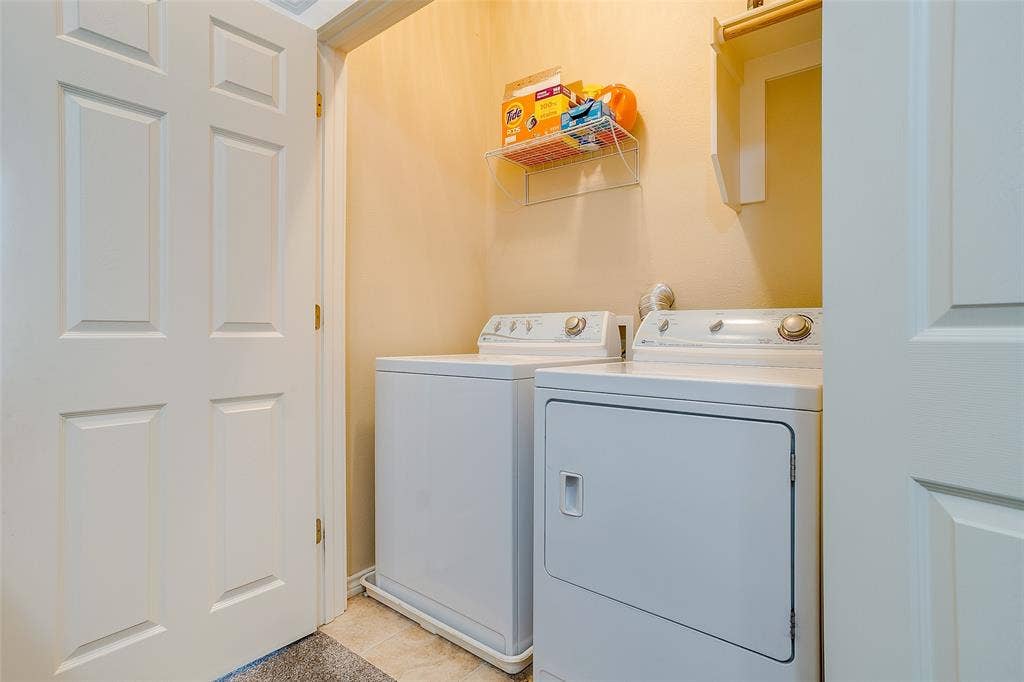1211 S Adams Street, Fort Worth, TX 76104 Dedicated laundry area featuring a tile floor, wall-mounted shelving, and a six-panel interior door