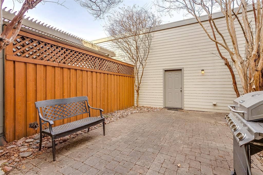 1211 S Adams Street, Fort Worth, TX 76104 Paved patio featuring a wood privacy fence with lattice top, tan siding, and an exterior door