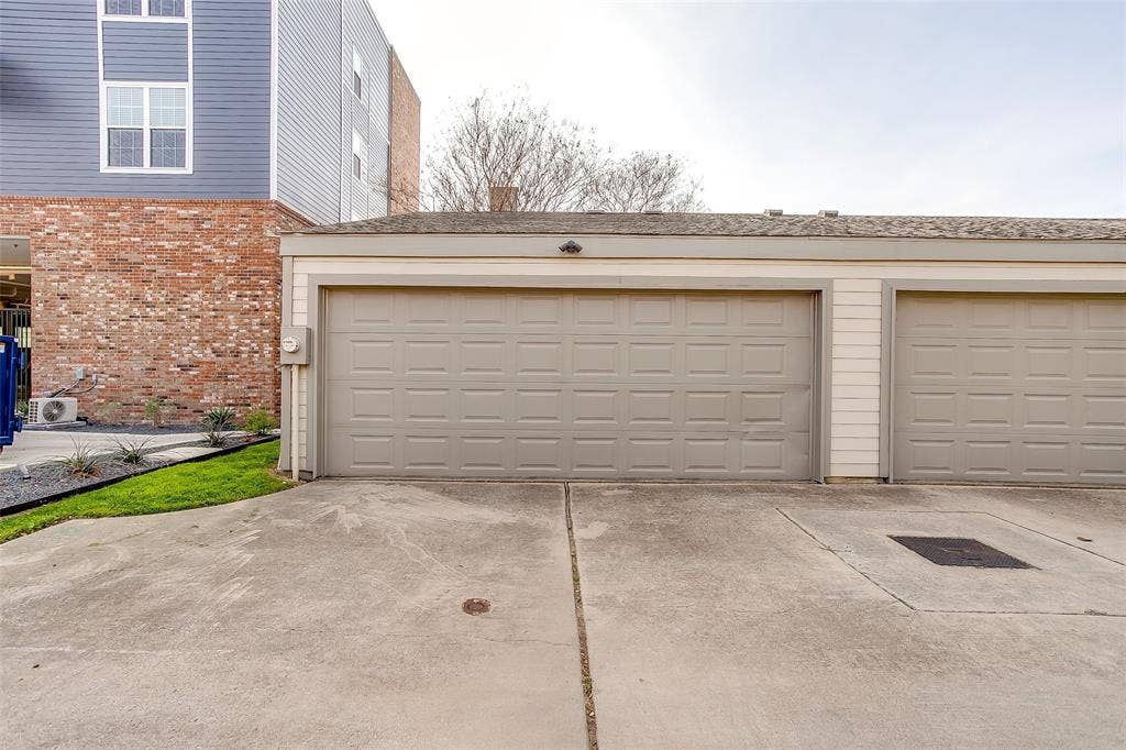 1211 S Adams Street, Fort Worth, TX 76104 Two-car garage featuring panel-style doors and a shingled roofline