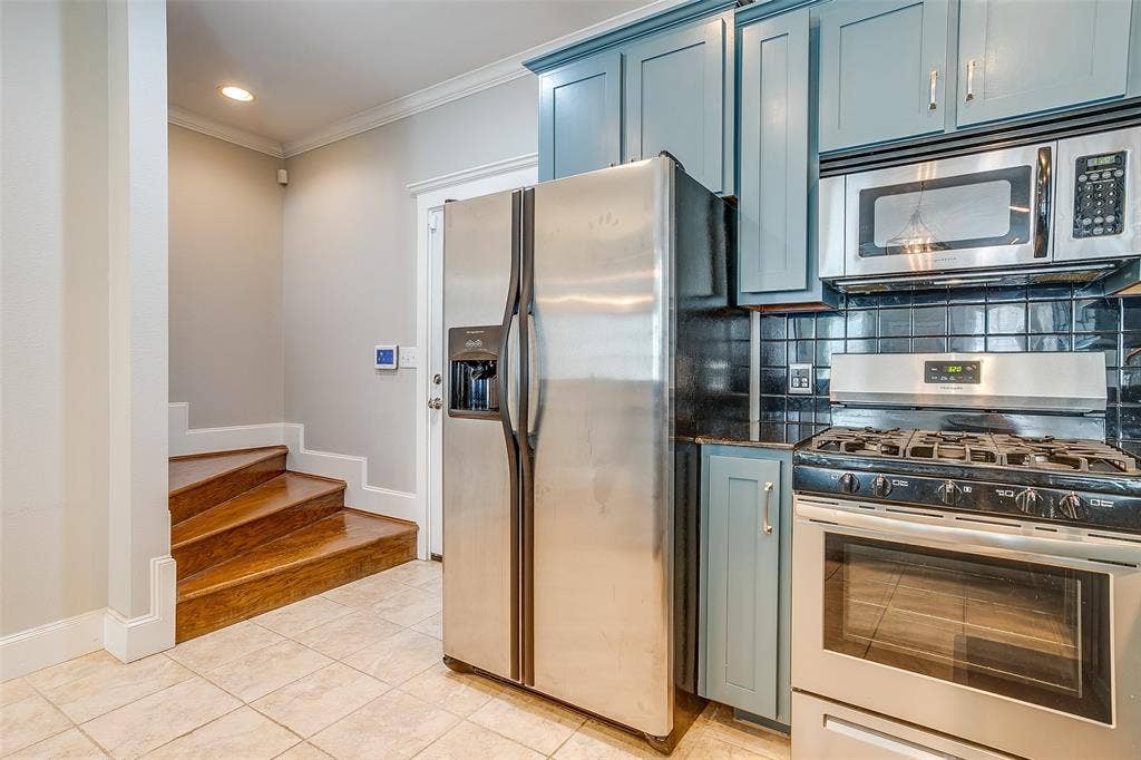 1211 S Adams Street, Fort Worth, TX 76104 Kitchen featuring slate blue cabinetry, black subway tile backsplash, stainless steel appliances, and a gas range