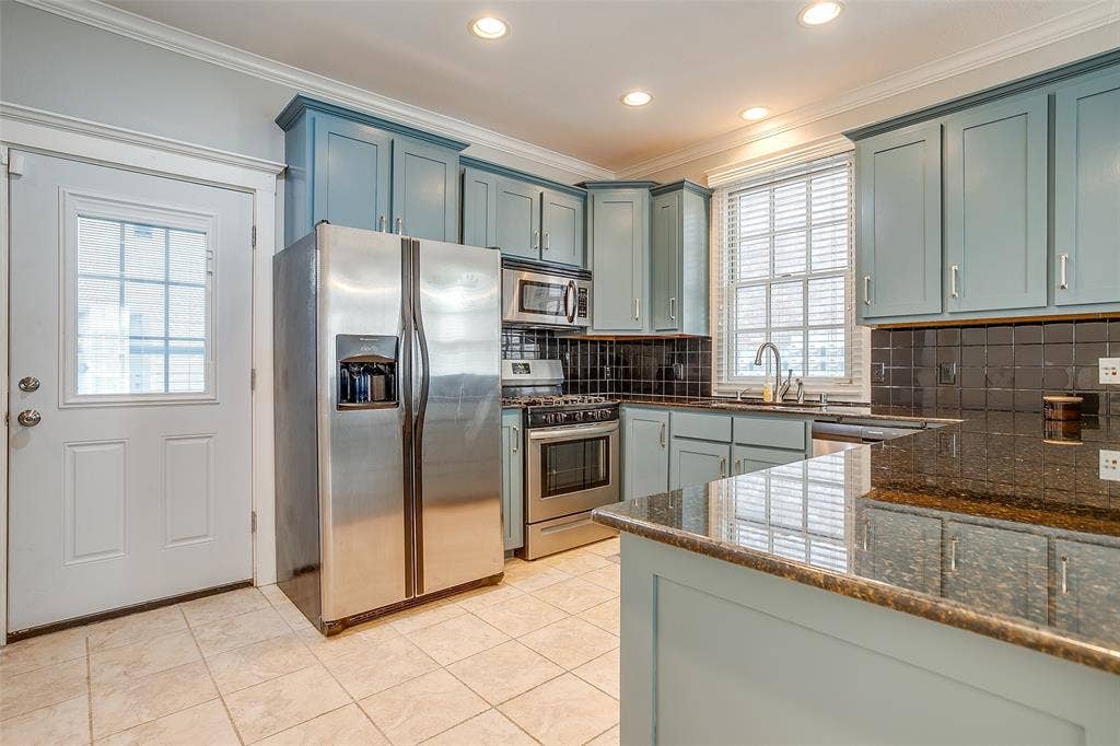 1211 S Adams Street, Fort Worth, TX 76104 Kitchen featuring light blue cabinetry, dark granite countertops, stainless steel appliances, a dark tiled backsplash, and recessed lighting
