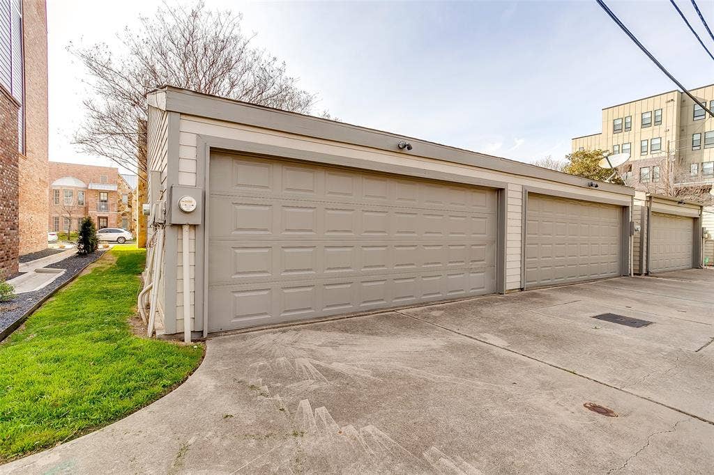 1211 S Adams Street, Fort Worth, TX 76104 Detached three-car garage featuring panel-style doors and exterior sconce lighting