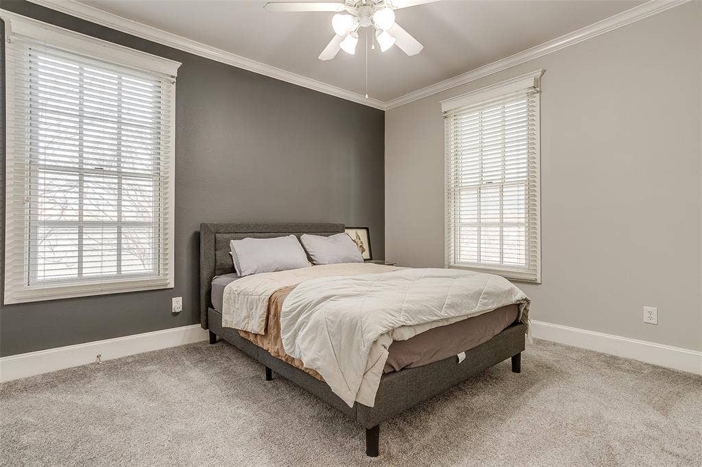 1211 S Adams Street, Fort Worth, TX 76104 Bedroom featuring gray wall accent, light gray walls, white crown molding, white baseboards, and light gray carpeting