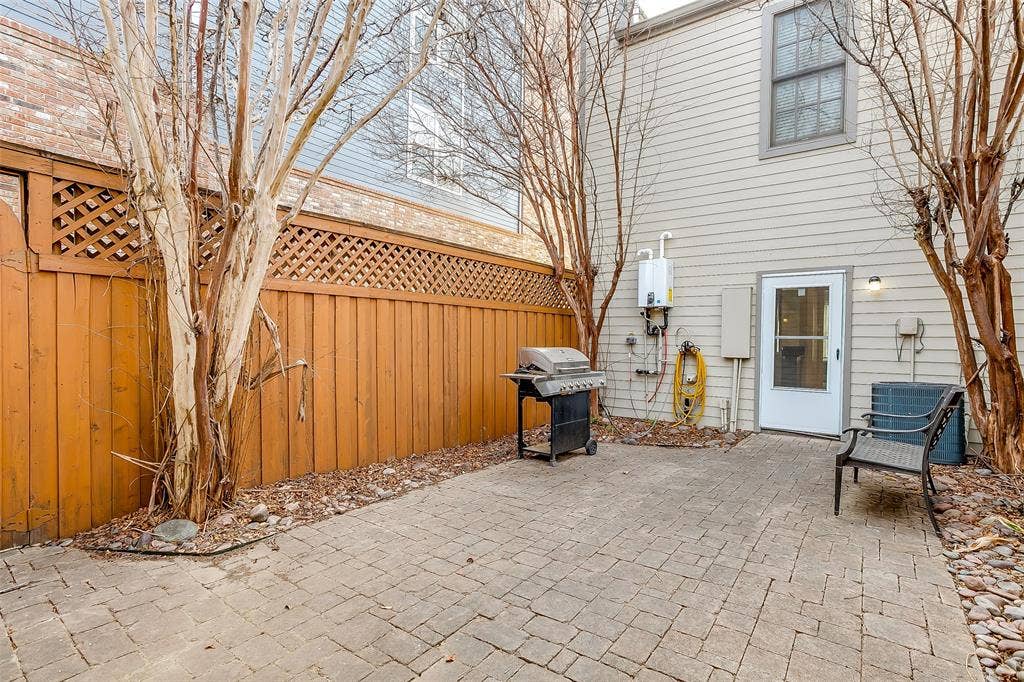 1211 S Adams Street, Fort Worth, TX 76104 Paved patio area featuring brick-patterned pavers and a wood privacy fence with lattice detailing