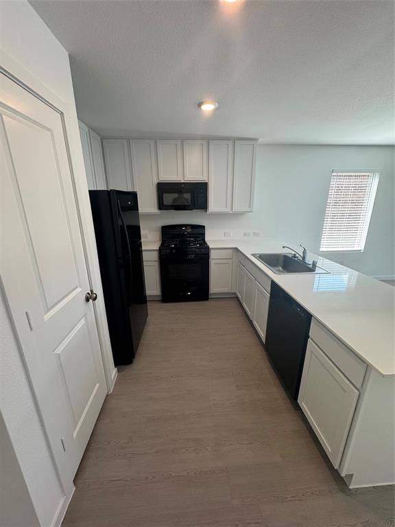 1271 Falcon Heights, Forney, TX 75126 Kitchen with light countertops, a peninsula, black appliances, white cabinets, and a textured ceiling